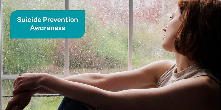 woman in darkened room looking out window